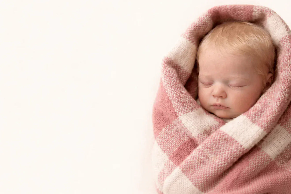 Lifelike reborn baby doll sleeping in a pink blanket